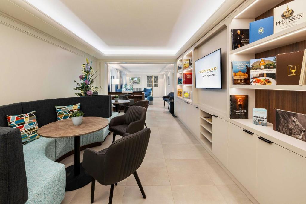 a waiting room with a table and chairs at Courtyard by Marriott Hamburg Airport in Hamburg