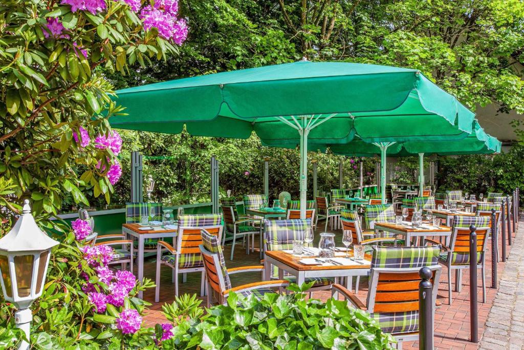 a group of tables and chairs under a green umbrella at Courtyard by Marriott Hamburg Airport in Hamburg