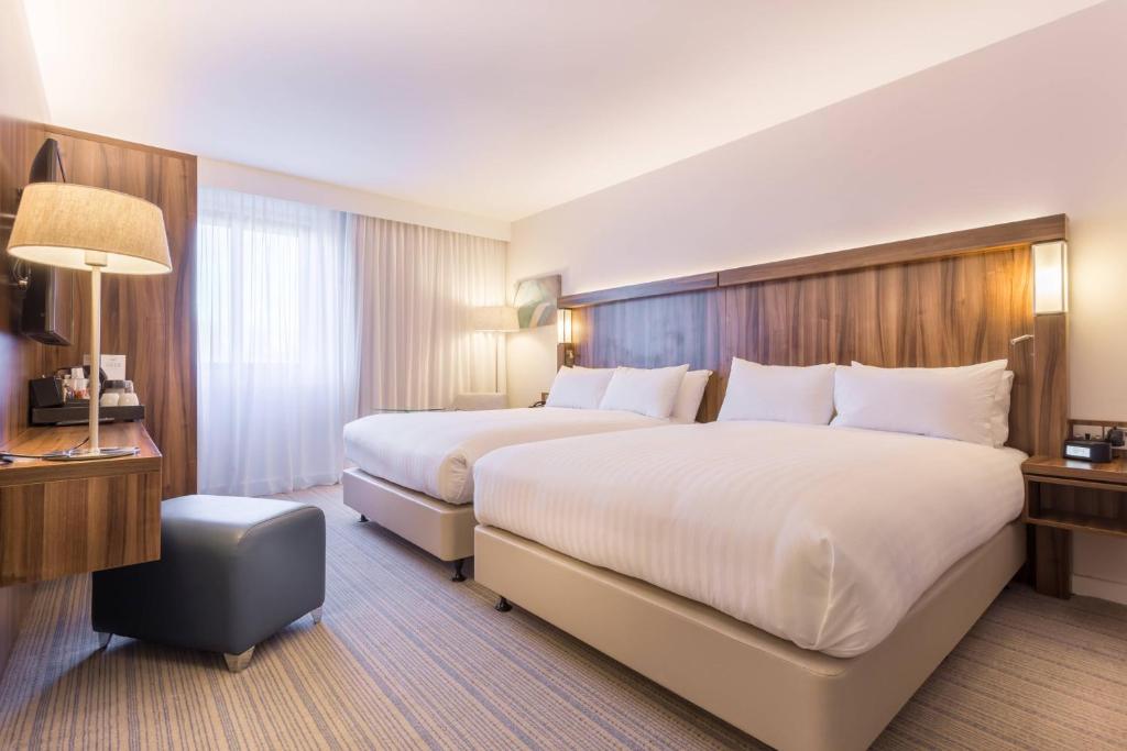 a large hotel room with two beds and a lamp at Courtyard by Marriott Glasgow Airport in Paisley