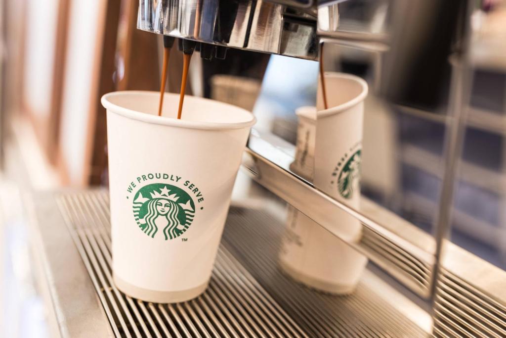 three coffee cups sitting on a shelf in a coffee shop at Courtyard by Marriott Glasgow Airport in Paisley