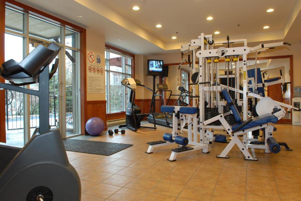 a gym with treadmills and machines in a room at Sommet Des Neiges in Mont-Tremblant