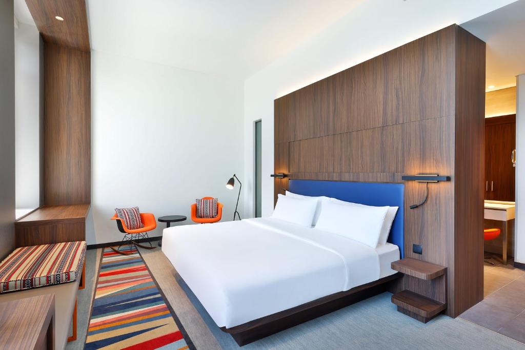 a bedroom with a large white bed and a desk at Aloft by Marriott Dubai Airport in Dubai