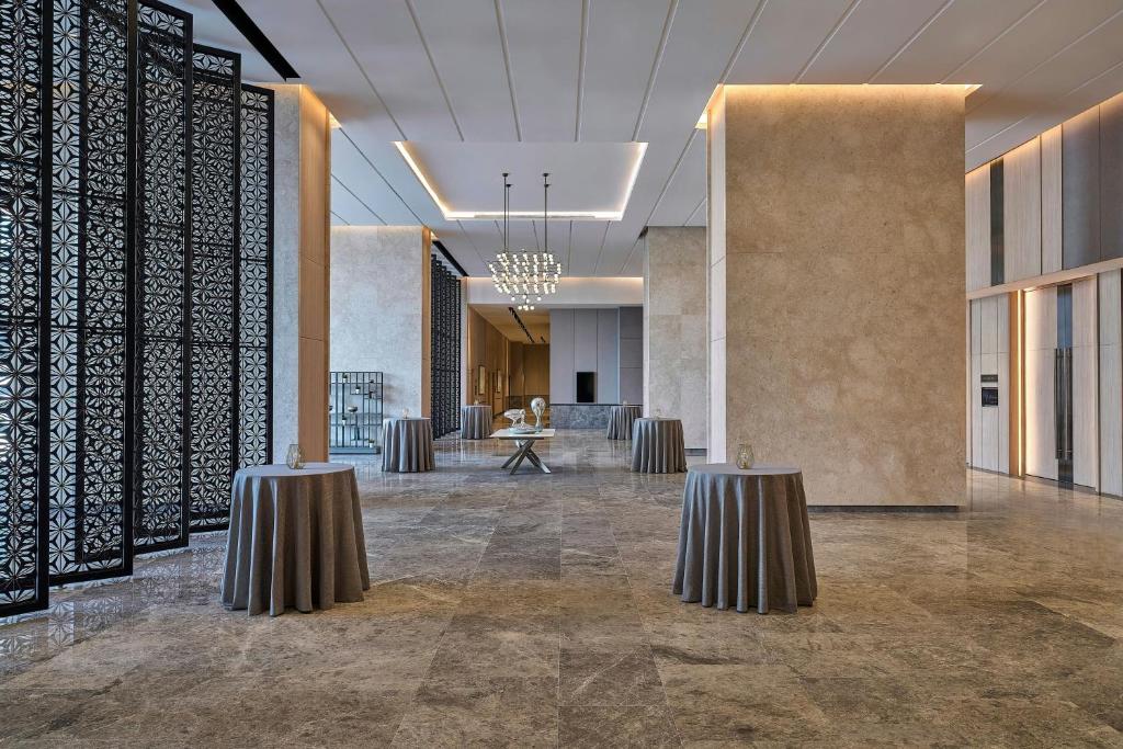 A formal hotel event foyer with cocktail tables and decorative screens.