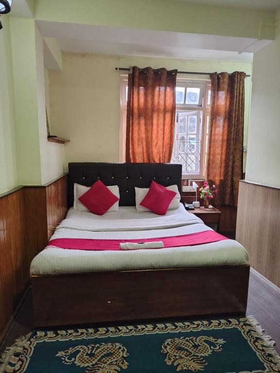 a bedroom with a large bed with red pillows at HOTEL TASHI NORLING Near Mall Road in Gangtok