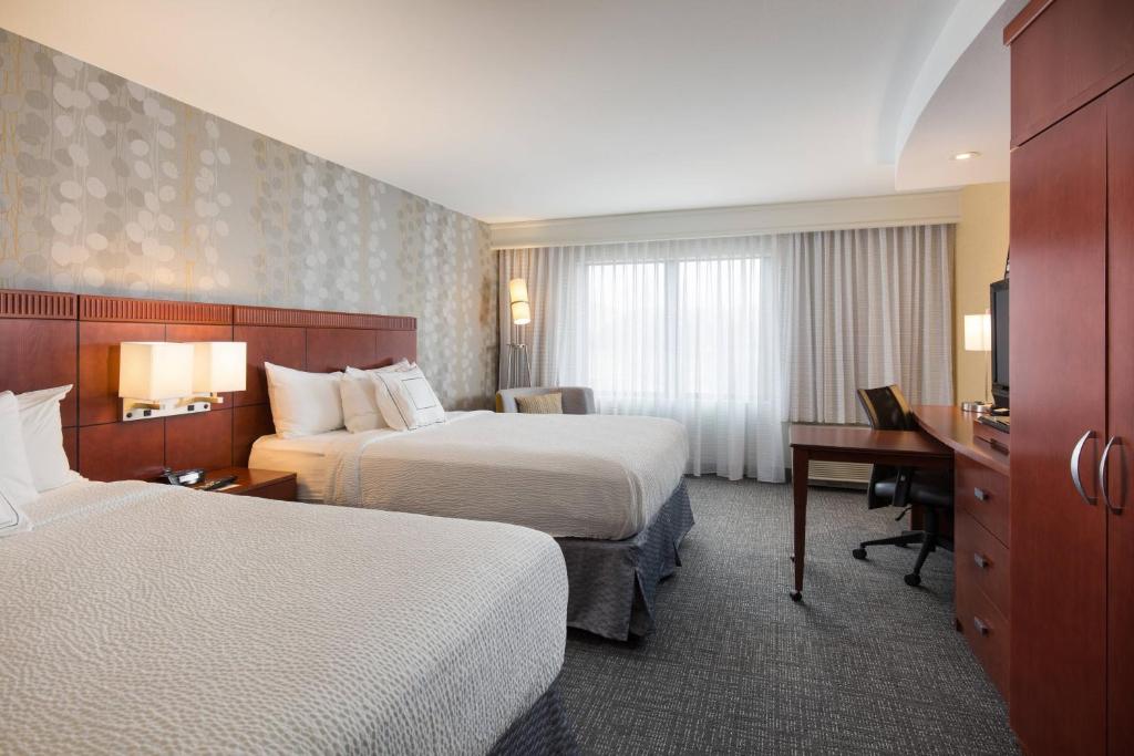 a hotel room with two beds and a desk at Courtyard Des Moines West-Jordan Creek in West Des Moines