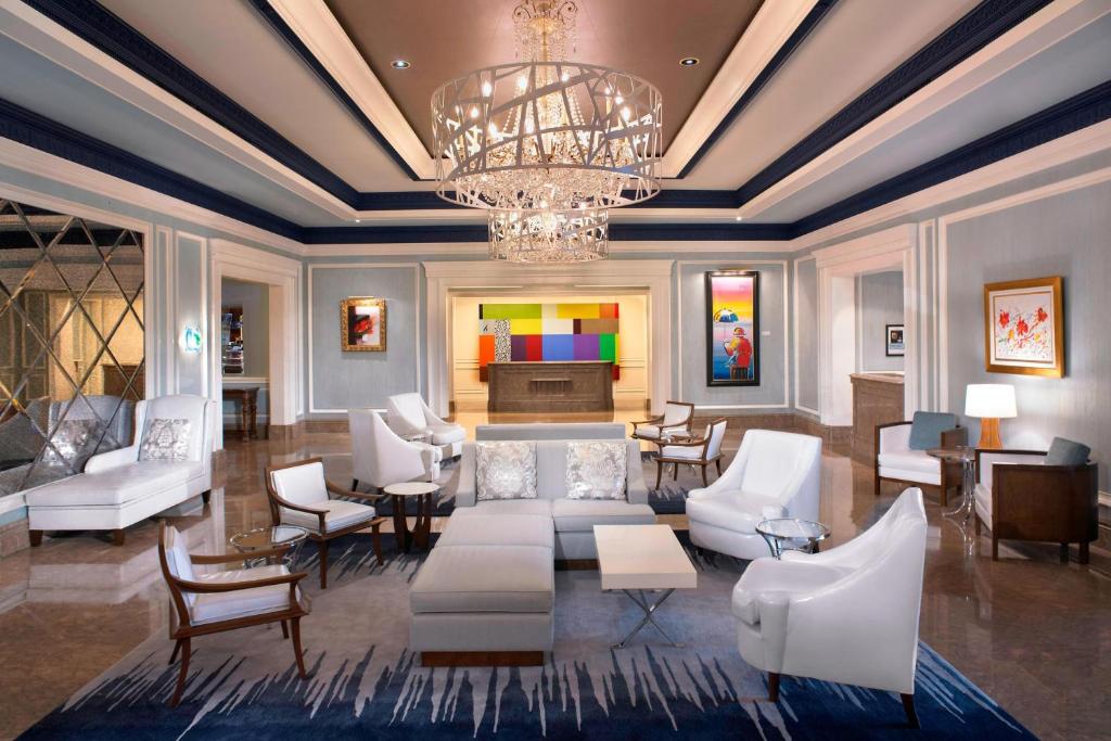 Una sala de estar con muebles blancos y una lámpara de araña. en The Henry, Autograph Collection, en Dearborn