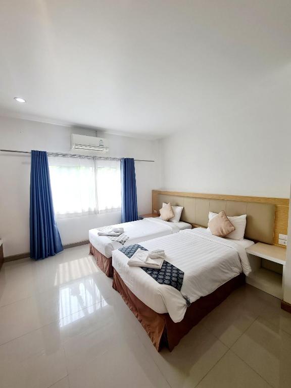 a bedroom with two beds and a window with blue curtains at Bualinn Resort in Nong Khai