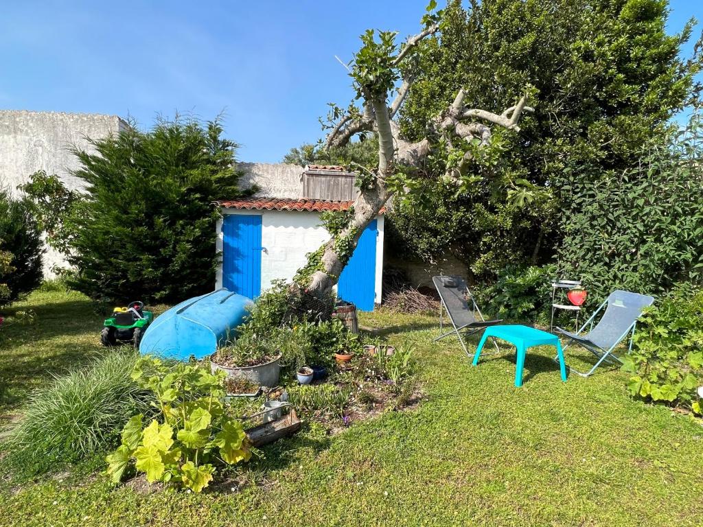 un jardin avec deux chaises et un hangar bleu dans l'établissement Au cœur d’un jardin ensoleillé, au Château-dʼOléron