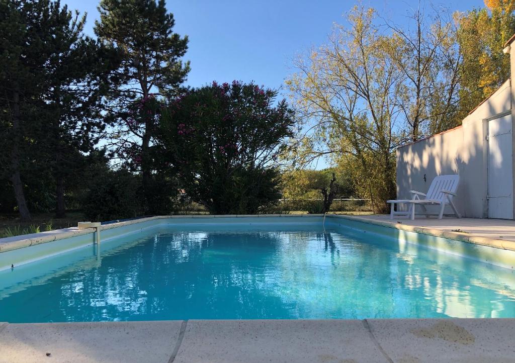 une piscine avec de l'eau bleue dans une cour dans l'établissement Paradis de verdure à Gibou, au Château-dʼOléron