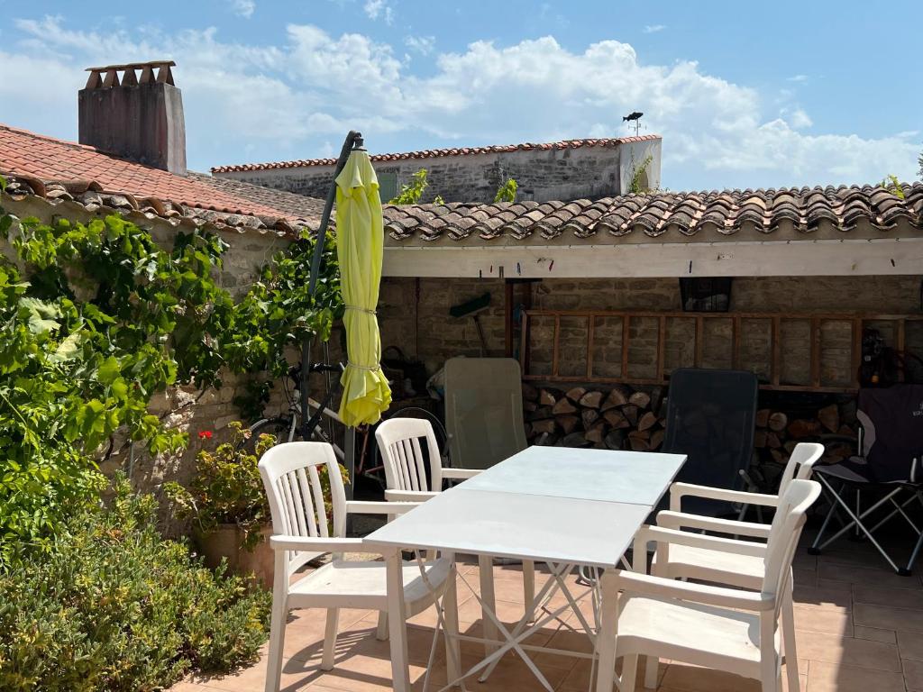une table et des chaises avec un parasol sur une terrasse dans l'établissement Maison agréable avec cour privée, à Dolus-d'Oléron