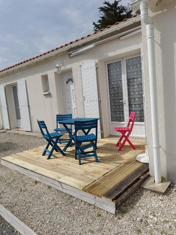 une terrasse en bois avec quatre chaises et une table dans l'établissement Forge 130, à Saint-Georges-dʼOléron