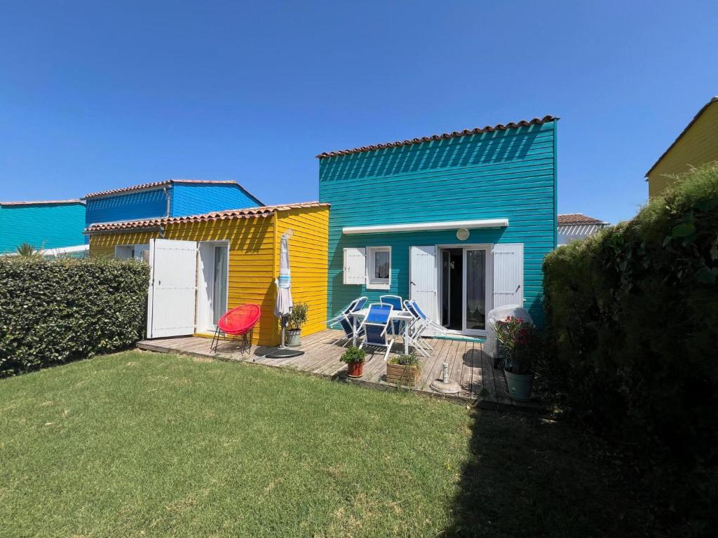 a colorful house with a table and chairs in a yard at Maison lumineuse au calme, pres mer in Le Château-dʼOléron