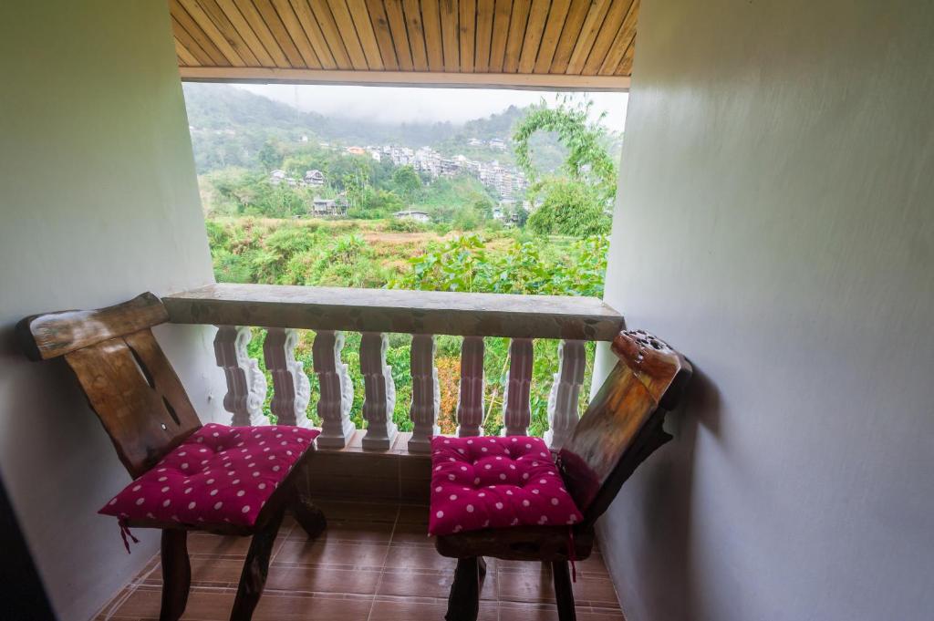 a pair of chairs sitting in front of a window at Rice Homestay in Banaue