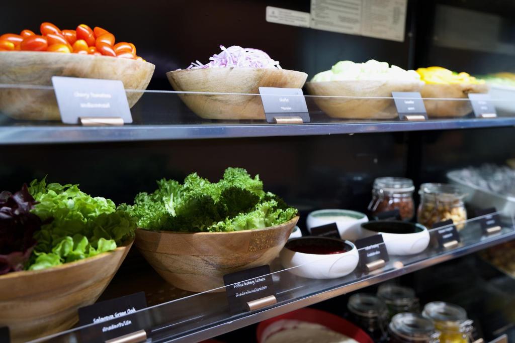 A chilled display of leafy greens, vegetables and toppings.