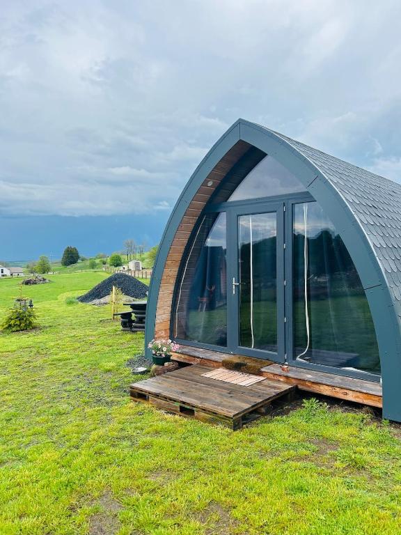 une maison en forme de dôme avec une terrasse en bois dans un champ dans l'établissement Chalet cosy en Aubrac, à Nasbinals