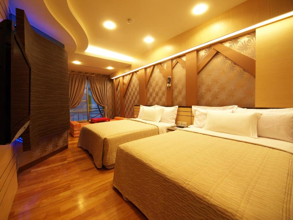a hotel room with two beds and a flat screen tv at Ibizakenting Hotel II in Kenting