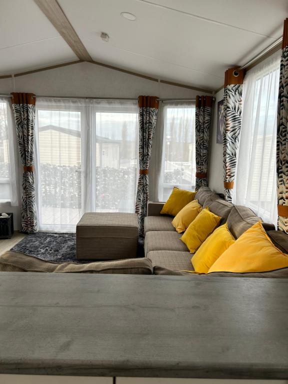 a living room with a couch with yellow pillows at Sunset Terrace Rockley Park Haven in Lytchett Minster