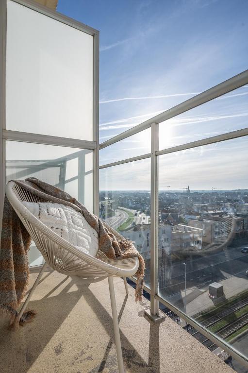 a rattan chair on a balcony with a view of a city at kindvriendelijk appartement "Sereno", De Haan-Wenduine in Wenduine
