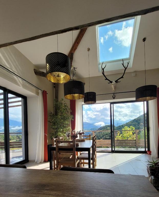 d'une salle à manger avec une table et de grandes fenêtres. dans l'établissement Maison La Valdiane vue lac et montagne, à Rousset