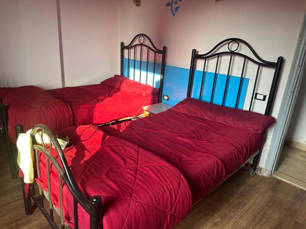 two beds with red covers in a room at oasis Hotel in Cairo