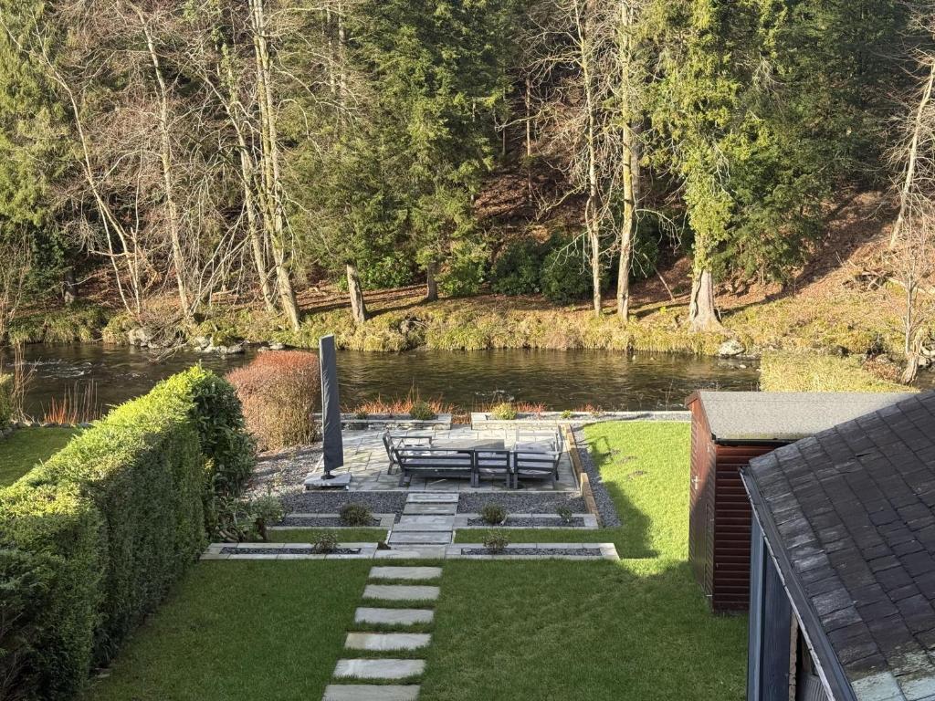 a view of a river with benches in the grass at Greta House in Keswick