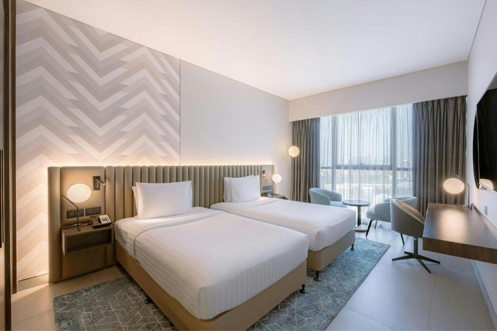 a hotel room with two beds and a desk at Courtyard by Marriott World Trade Centre, Dubai in Dubai