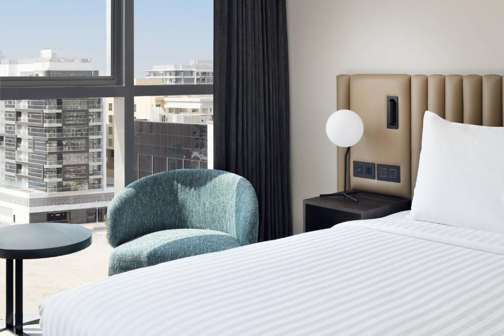 a bedroom with a bed and a chair and a window at Courtyard by Marriott World Trade Centre, Dubai in Dubai