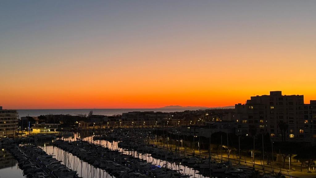 un coucher de soleil sur une ville avec port de plaisance dans l'établissement Vue Magique Port & Mer et un Panorama Unique depuis la Chambre, à Mauguio