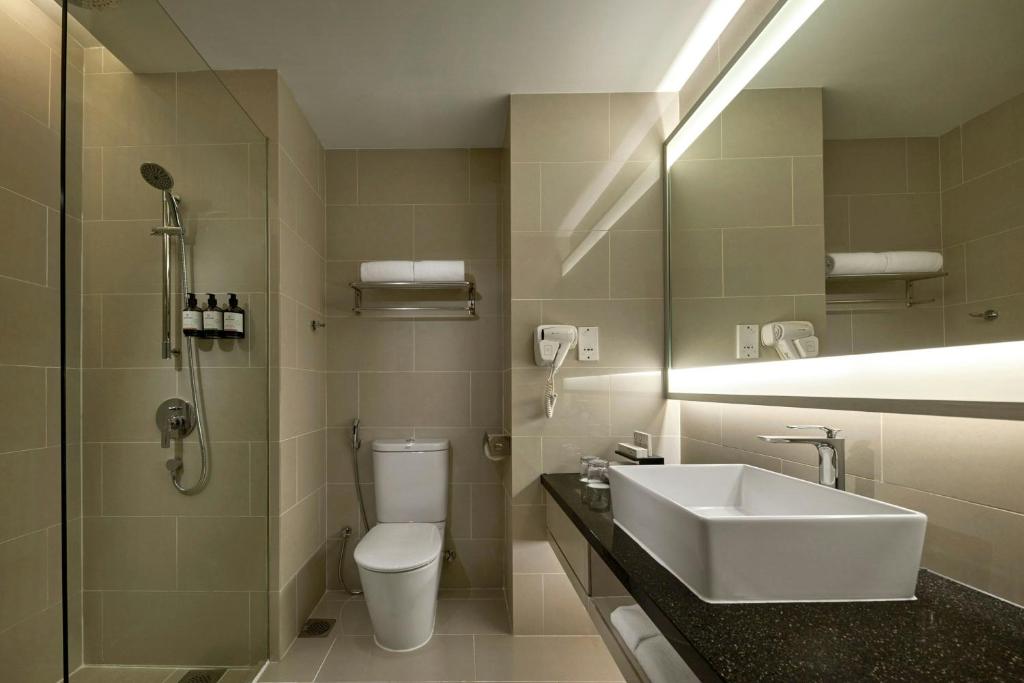 A compact tiled bathroom with a walk-in shower, toilet and vessel sink.