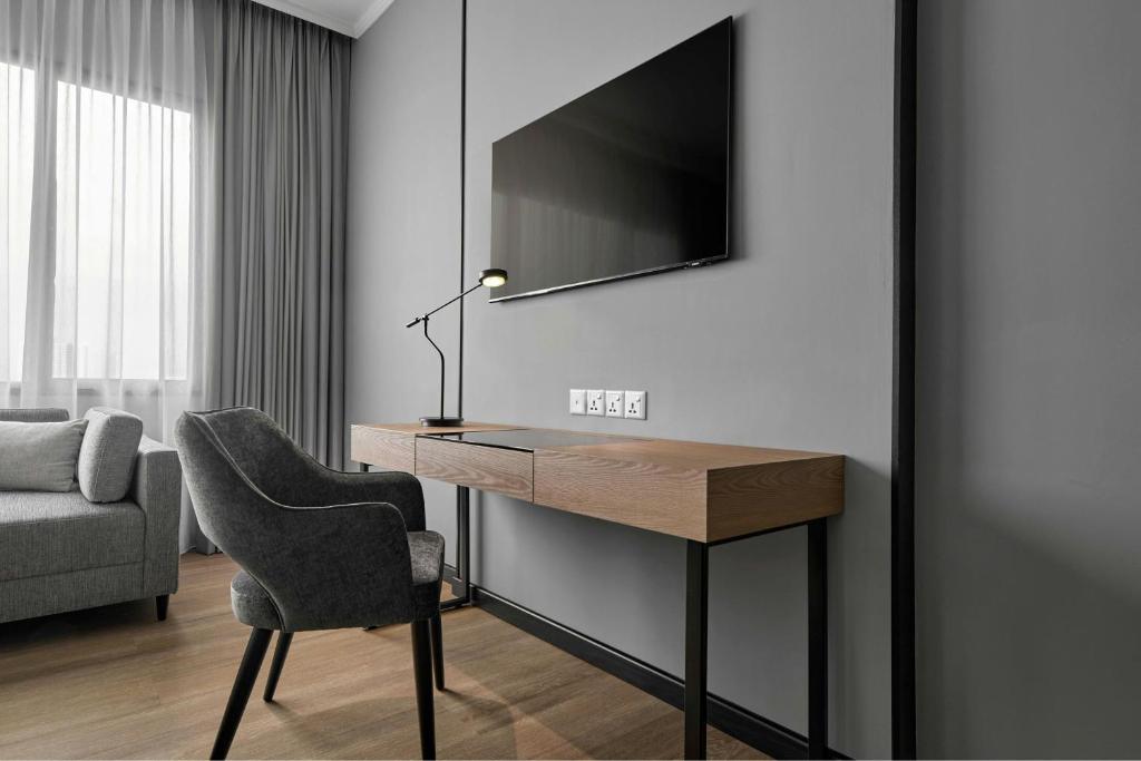 A compact desk sits beside a lounge chair and wall-mounted television.
