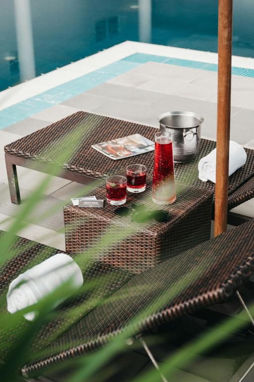 A poolside lounger arranged with drinks, towels, and a small reading item.