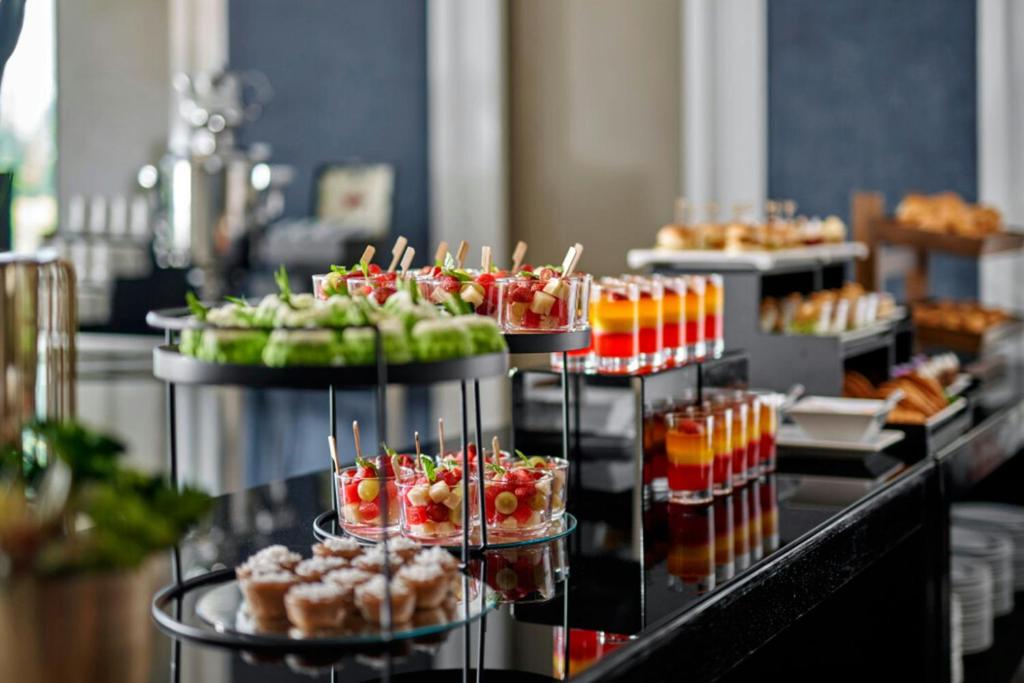 A professionally styled buffet display of fruit, drinks, pastries and small desserts.