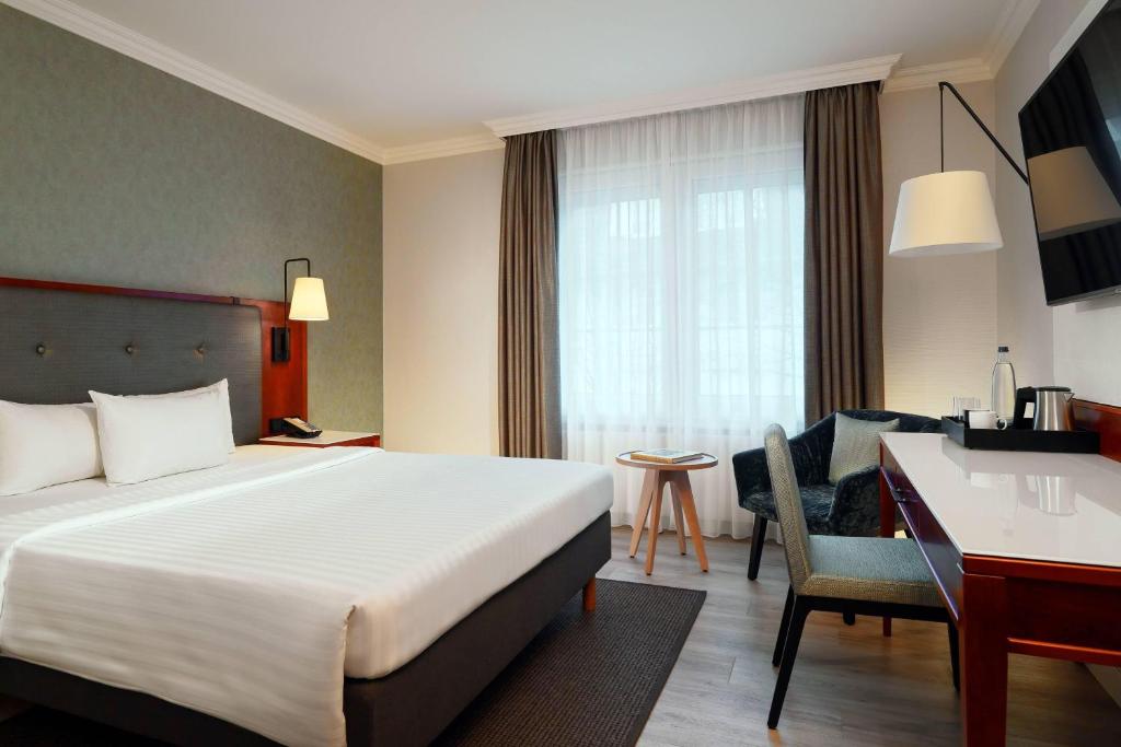 a hotel room with a bed and a desk at Courtyard by Marriott Hamburg Airport in Hamburg
