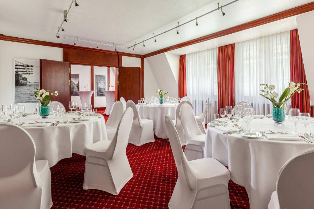 a banquet room with white tables and white chairs at Courtyard by Marriott Hamburg Airport in Hamburg