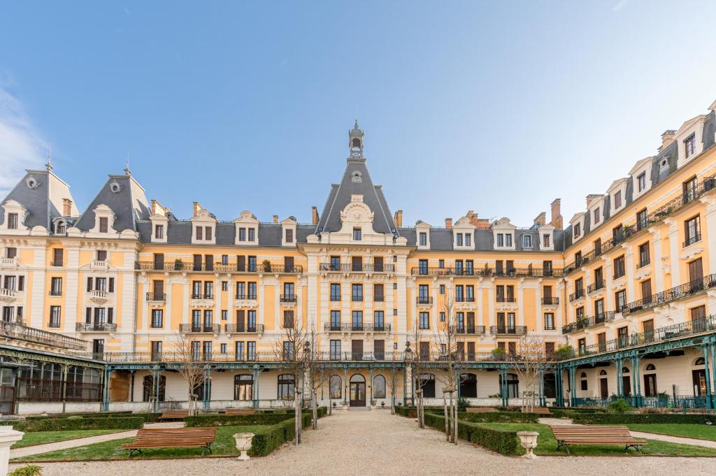 un grand bâtiment avec bancs devant lui dans l'établissement Smartstay L Ecrin Aix Les Bains, à Aix-les-Bains