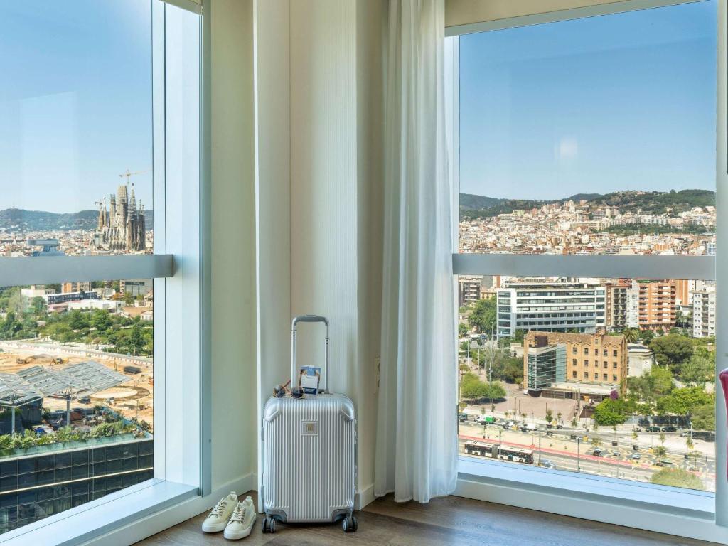 a suitcase is sitting in front of a window at Novotel Barcelona City in Barcelona