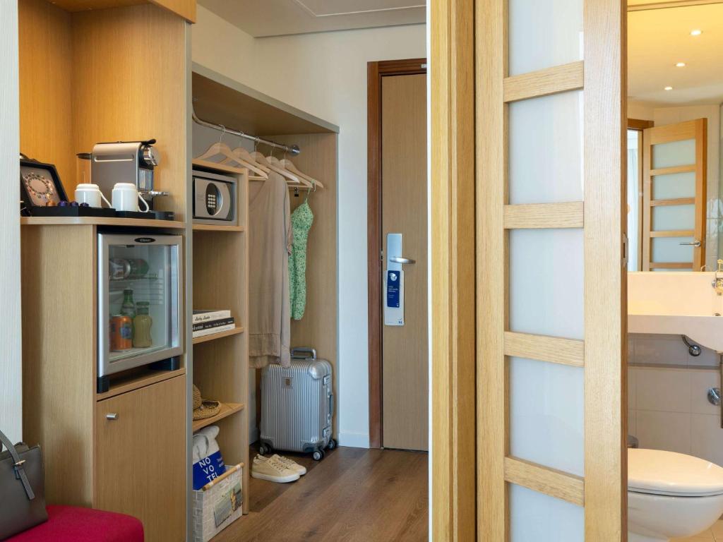 a room with a closet with a toilet and a door at Novotel Barcelona City in Barcelona