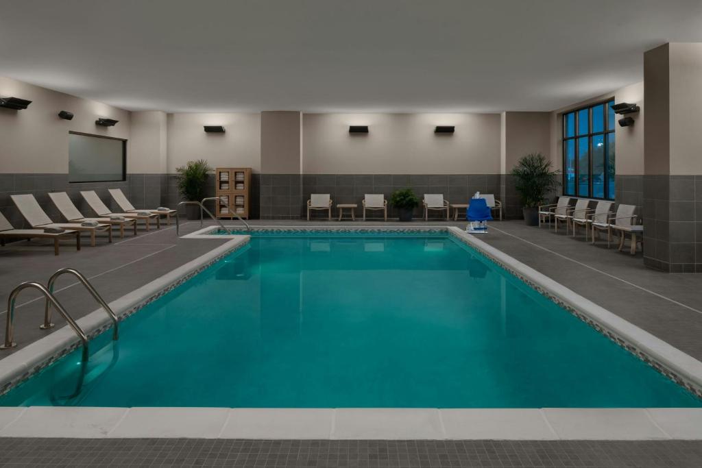 兰辛AC Hotel by Marriott Lansing University Area的酒店房间里的游泳池，配有桌椅