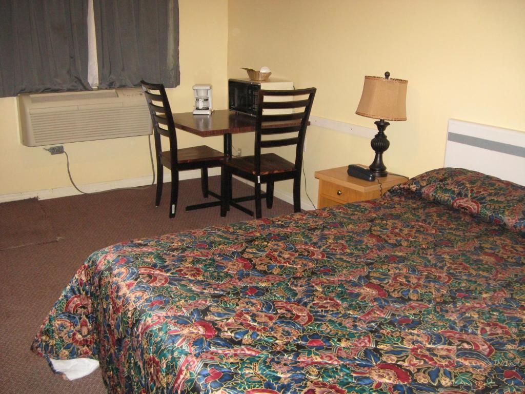 a hotel room with a bed and a table and chairs at Pals Motel and RV Park in Medicine Hat