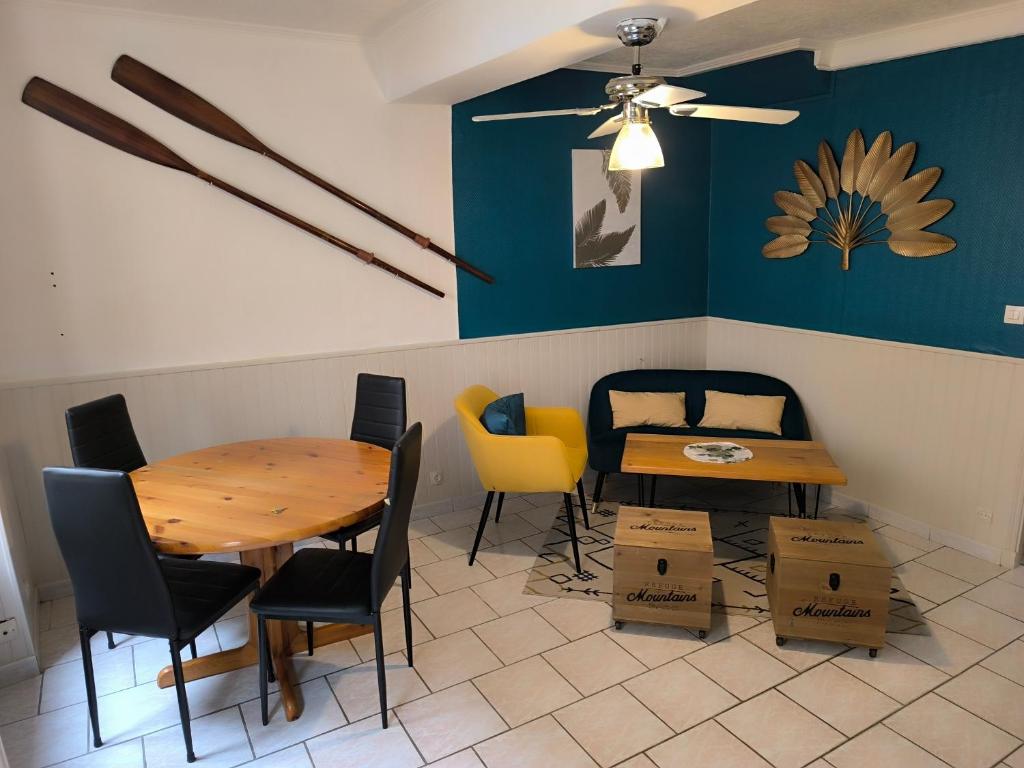 a dining room with a table and chairs and a ceiling fan at Le refuge des tanneurs in Tannay