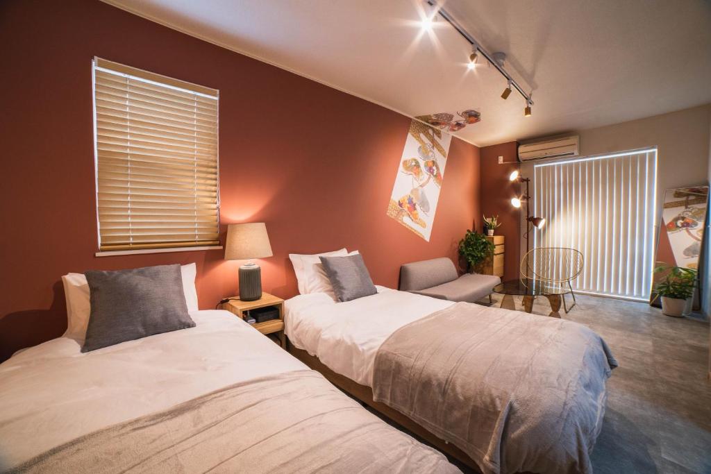 a bedroom with two beds and a chair and window at New open! Dream ASUNARO 5 minuites from Shinsaibashi in Osaka