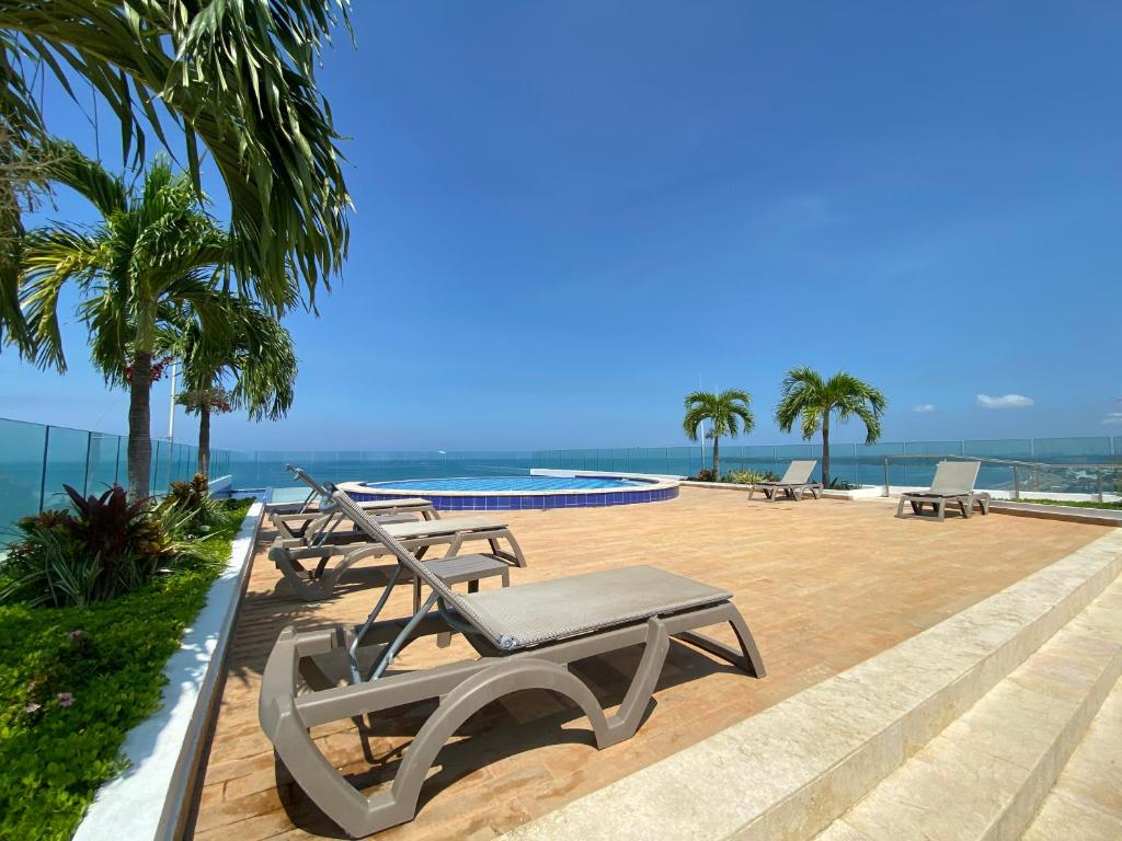 卡塔赫纳Apartment with direct access to the Sea in CTG的一个带椅子的庭院、一个游泳池和大海