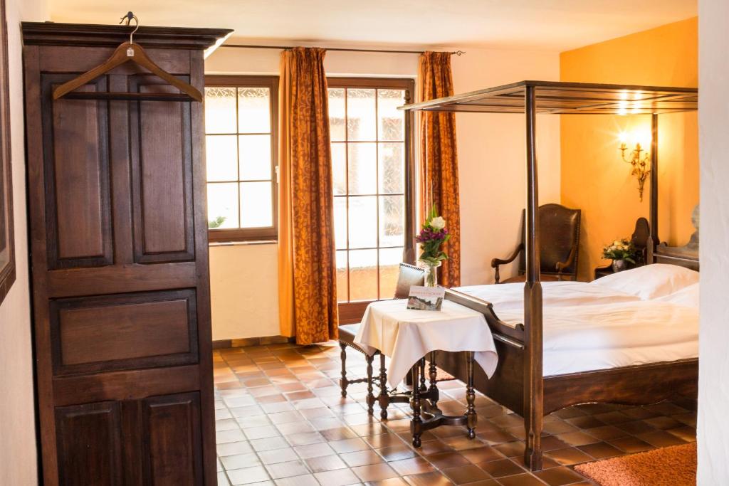 a bedroom with a canopy bed and a table at WAGNERS Hotel Greifen-Post in Feuchtwangen