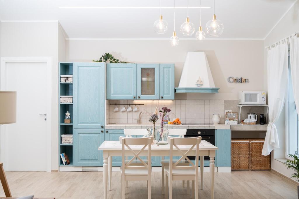 kuchnia z niebieskimi szafkami i stołem z krzesłami w obiekcie Otium Rooms / Camere e Appartamenti w mieście Morrovalle