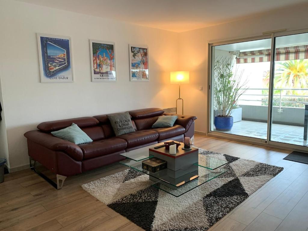a living room with a brown couch and a glass table at Charmant 3 pièces vue mer in Antibes