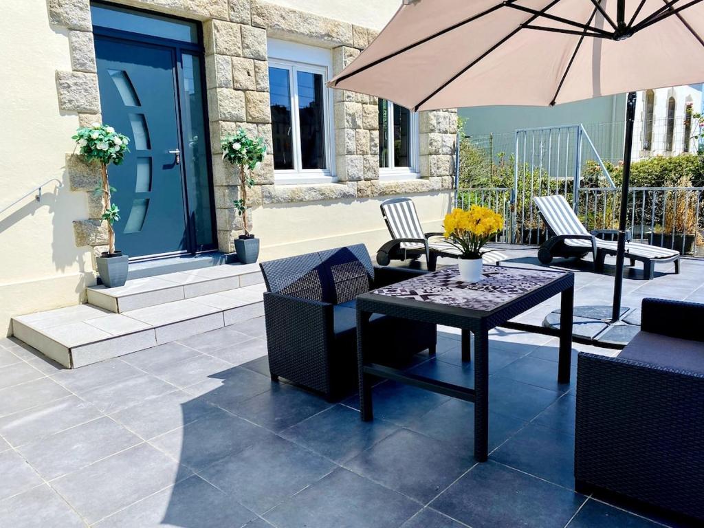 un patio avec une table, des chaises et un parasol dans l'établissement Spacieux appartement terrasse au coeur de la ville, à Quimperlé