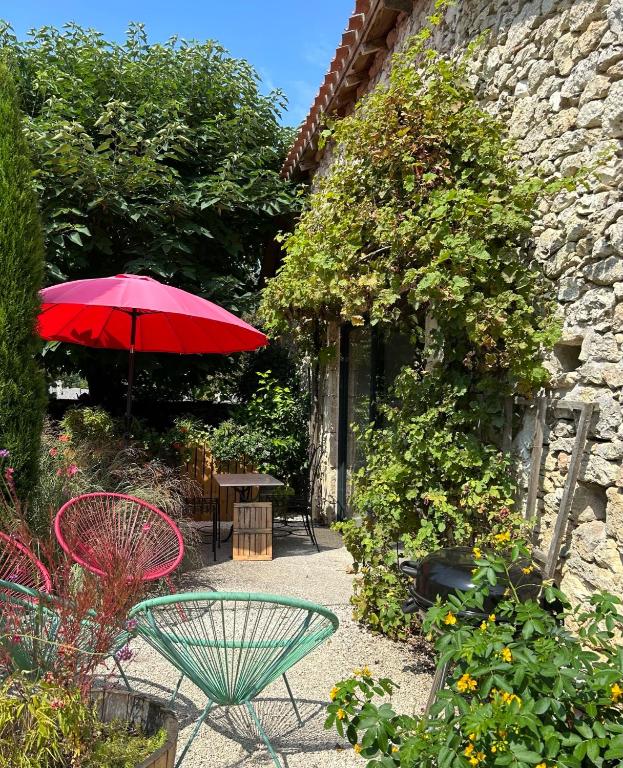 d'une terrasse avec une table et un parasol rouge. dans l'établissement La Grange de la Maison des chats - Gîte en Quercy, à Saint-Amans-du-Pech