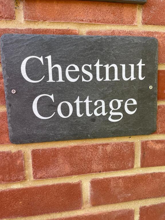 a sign for chestnut cottage on a brick wall at Chestnut Cottage in Great Ellingham