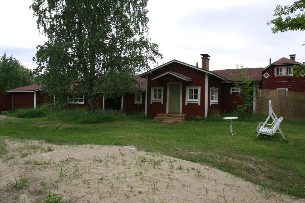 une maison rouge avec une chaise blanche dans la cour dans l'établissement Tähdikki Cottage, à Kalmari