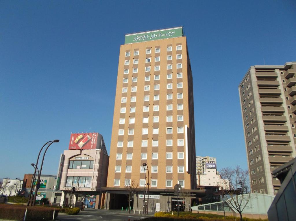 Un grand bâtiment avec un panneau en haut dans l'établissement Hotel Route-Inn Hirosaki Ekimae, à Hirosaki